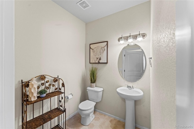 bathroom featuring toilet, a sink, and baseboards