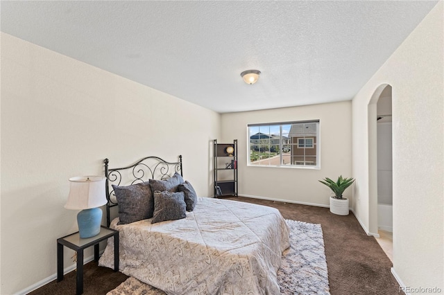 carpeted bedroom with arched walkways, a textured ceiling, and baseboards