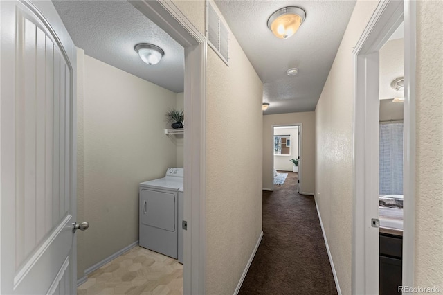 washroom featuring washer / clothes dryer, baseboards, and a textured wall
