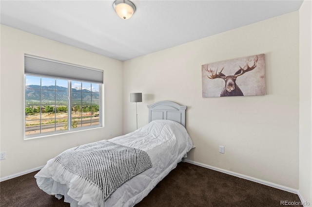 carpeted bedroom featuring baseboards and a mountain view