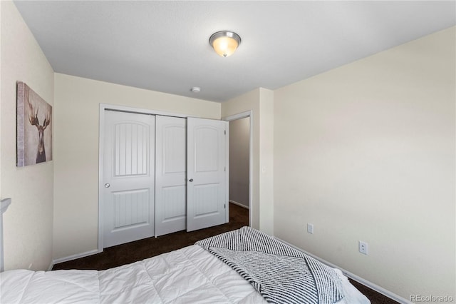 carpeted bedroom featuring a closet and baseboards