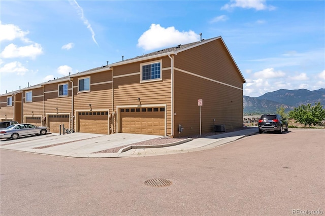 view of front facade featuring a mountain view, an attached garage, driveway, and central AC