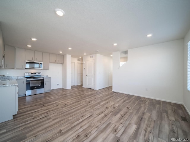 kitchen featuring stainless steel appliances, recessed lighting, open floor plan, and wood finished floors