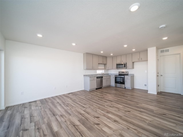 kitchen with light wood finished floors, visible vents, appliances with stainless steel finishes, light countertops, and gray cabinetry