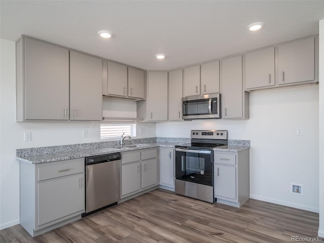 kitchen featuring baseboards, appliances with stainless steel finishes, wood finished floors, and recessed lighting