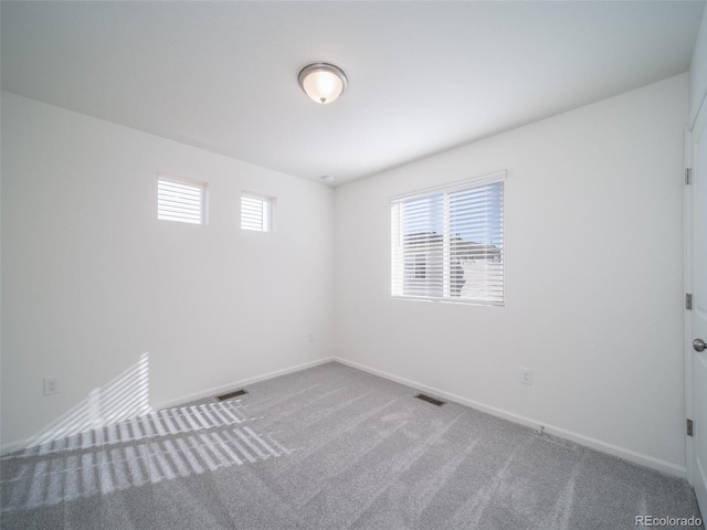 carpeted spare room with baseboards and visible vents