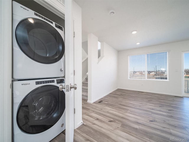 washroom featuring stacked washer and clothes dryer, recessed lighting, wood finished floors, laundry area, and baseboards