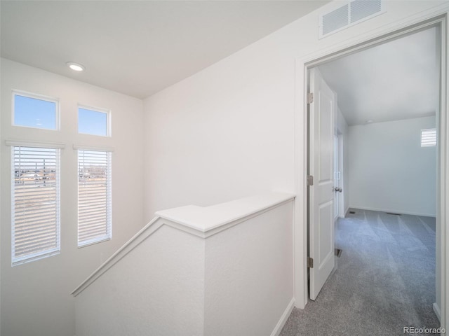 hall with baseboards, visible vents, and carpet flooring