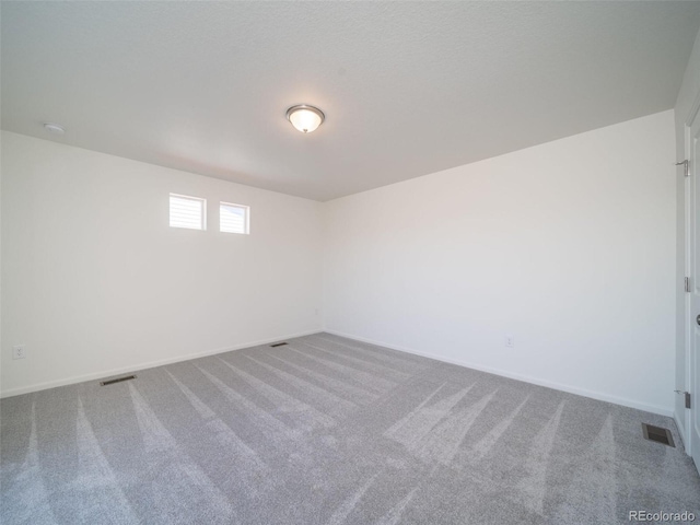 carpeted spare room featuring visible vents and baseboards