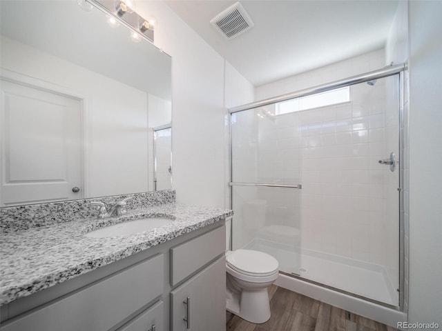 bathroom featuring toilet, a shower stall, visible vents, and wood finished floors