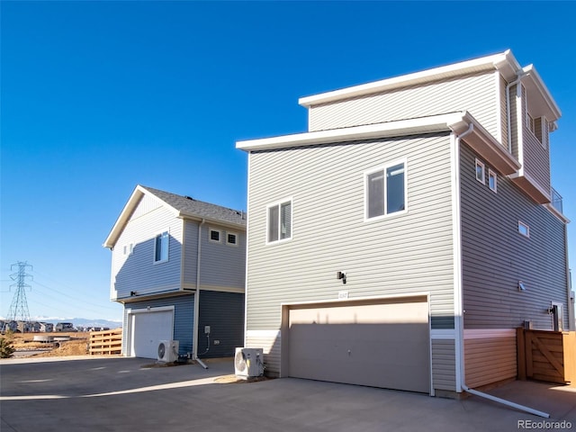 back of property with a garage, ac unit, and fence