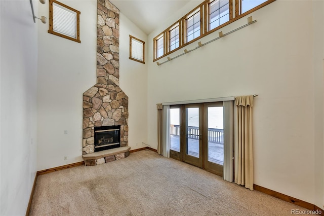 unfurnished living room with a fireplace, plenty of natural light, light colored carpet, and a high ceiling