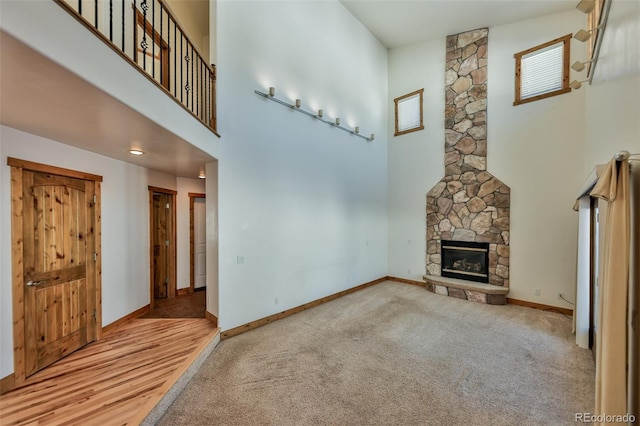 unfurnished living room with a high ceiling, light carpet, and a fireplace