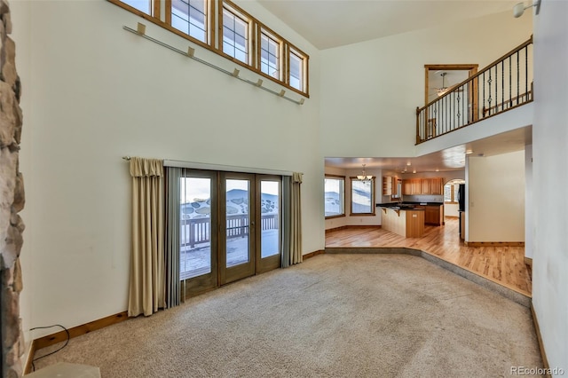 unfurnished living room featuring a mountain view, light colored carpet, french doors, and a high ceiling