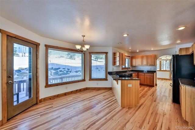 kitchen with a kitchen bar, sink, an inviting chandelier, light wood-type flooring, and pendant lighting