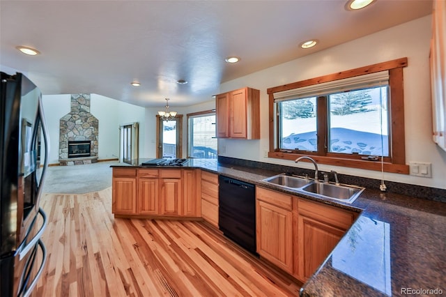 kitchen featuring sink, kitchen peninsula, pendant lighting, a fireplace, and black appliances