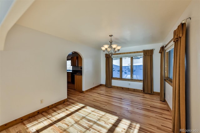 unfurnished dining area featuring a notable chandelier and light hardwood / wood-style flooring