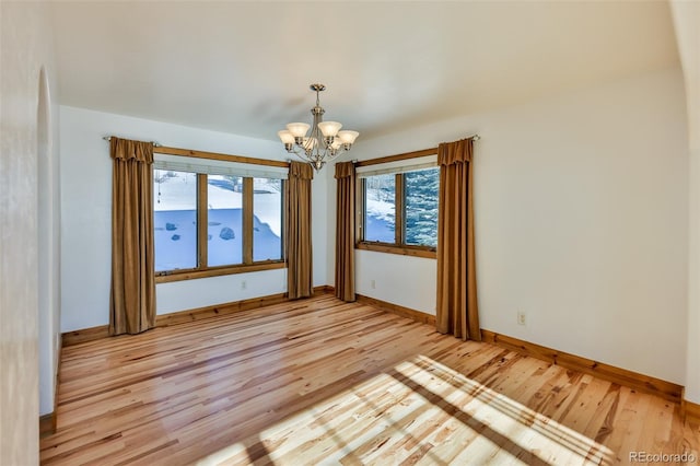 empty room with an inviting chandelier and light hardwood / wood-style flooring