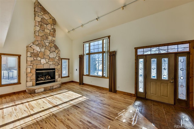 entryway featuring hardwood / wood-style flooring, track lighting, a fireplace, and high vaulted ceiling