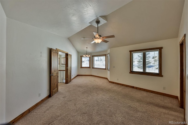 carpeted spare room with ceiling fan with notable chandelier and vaulted ceiling