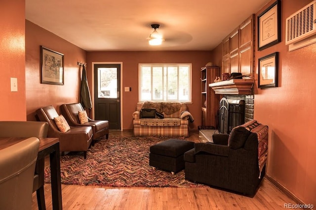 living room with ceiling fan, a fireplace, and light hardwood / wood-style flooring