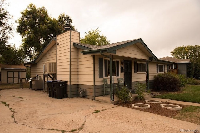 6213 Gray St, Arvada, CO 80003 - view of front of home featuring a patio area, a chimney, an outdoor structure, and a storage shed