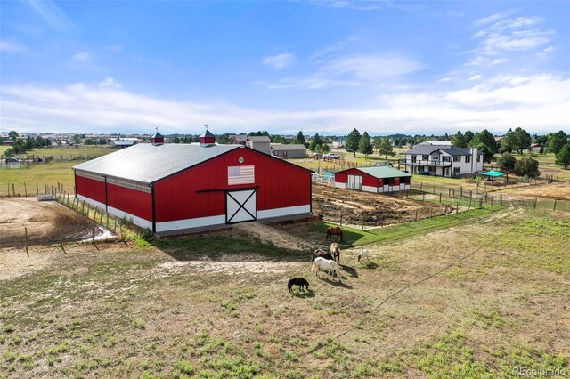 view of pole building with a rural view, fence, and a lawn