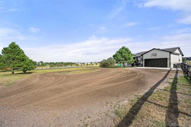 exterior space with an attached garage, dirt driveway, and fence