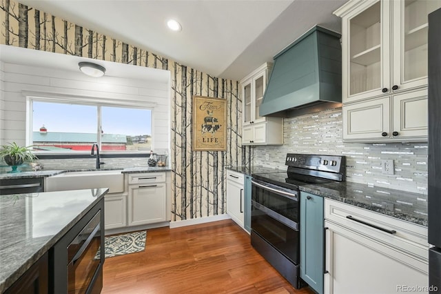 kitchen with dark stone counters, electric stove, dark wood-type flooring, and custom range hood