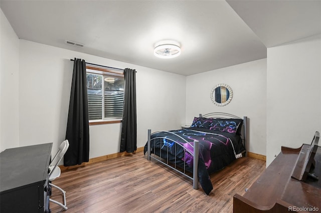 bedroom featuring wood finished floors, visible vents, and baseboards