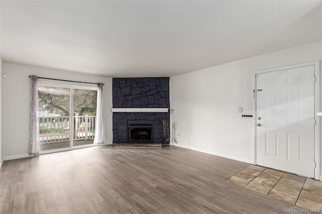 910 S Walden St Unit 106, Aurora, CO 80017 - unfurnished living room featuring wood finished floors, baseboards, and a stone fireplace