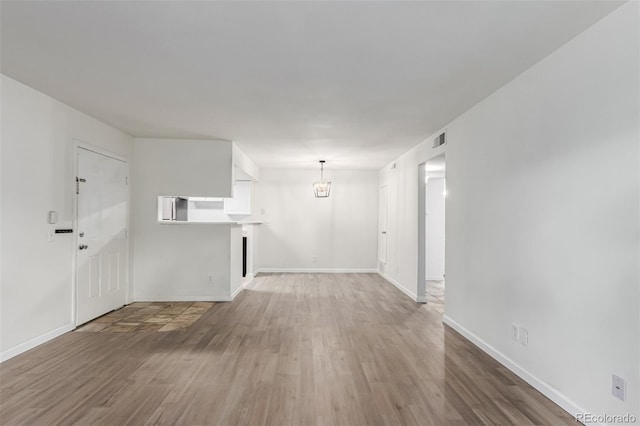 910 S Walden St Unit 106, Aurora, CO 80017 - unfurnished living room featuring wood finished floors, a chandelier, and baseboards