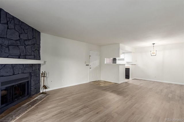 910 S Walden St Unit 106, Aurora, CO 80017 - unfurnished living room with a stone fireplace, light wood finished floors, and baseboards