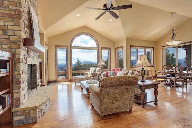 28800 Stonecrop Trl, Conifer, CO 80433 - living room featuring lofted ceiling, light wood-style flooring, ceiling fan, a stone fireplace, and a mountain view