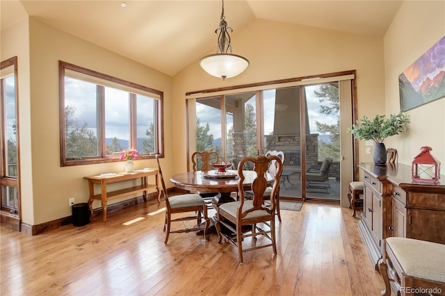 28800 Stonecrop Trl, Conifer, CO 80433 - dining area featuring plenty of natural light, vaulted ceiling, light wood-type flooring, and a fireplace