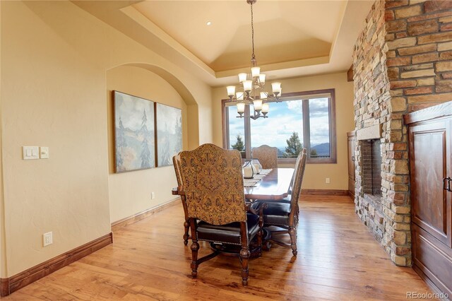 28800 Stonecrop Trl, Conifer, CO 80433 - dining area with light wood-style floors, a chandelier, a tray ceiling, and baseboards