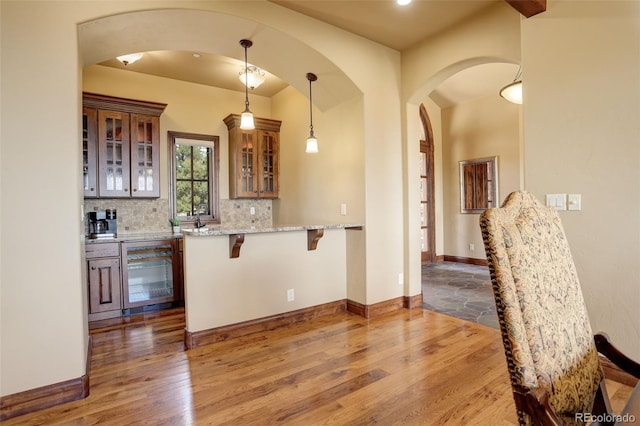 28800 Stonecrop Trl, Conifer, CO 80433 - kitchen featuring wine cooler, a kitchen breakfast bar, wood finished floors, arched walkways, and recessed lighting