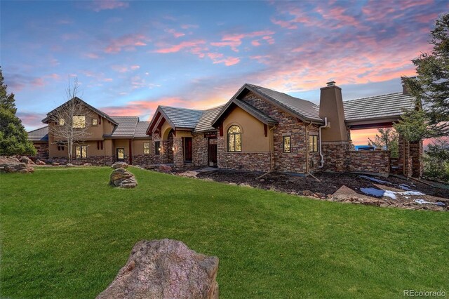 28800 Stonecrop Trl, Conifer, CO 80433 - view of front of house with stucco siding, a tile roof, a lawn, a chimney, and stone siding