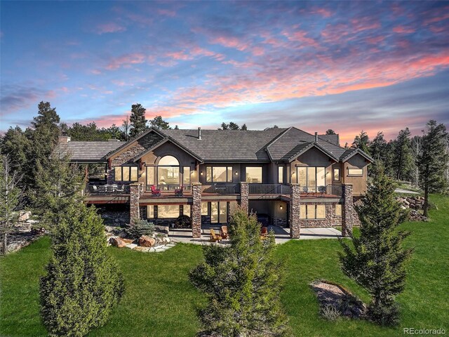 28800 Stonecrop Trl, Conifer, CO 80433 - rear view of house featuring stone siding, a patio area, a lawn, and a balcony