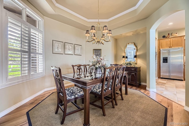 11070 Meade Ct, Westminster, CO 80031 - dining space with a raised ceiling, arched walkways, a chandelier, light wood finished floors, and crown molding
