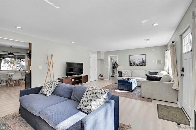 living area with wood finished floors, visible vents, and recessed lighting