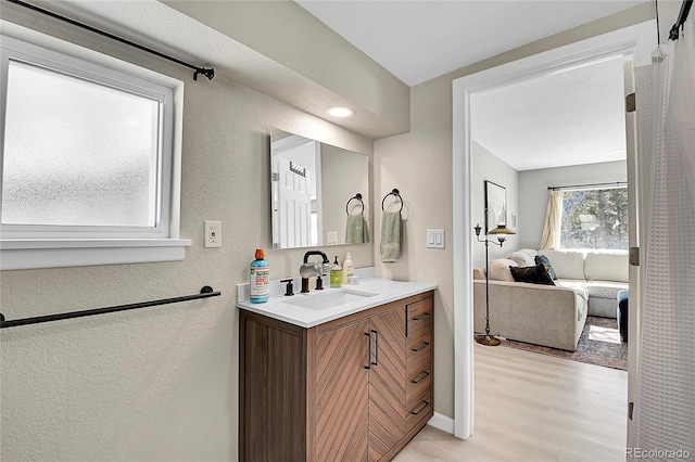 bathroom featuring baseboards, a textured wall, wood finished floors, ensuite bathroom, and vanity