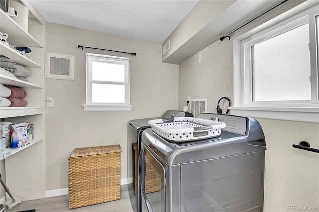 washroom featuring light wood-style flooring, laundry area, visible vents, baseboards, and washer and dryer