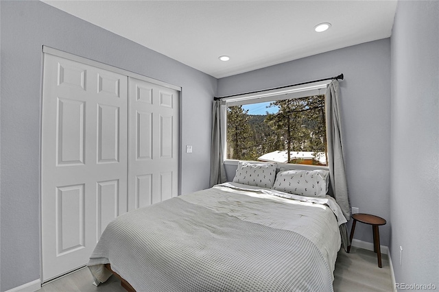 bedroom featuring light wood-type flooring, baseboards, a closet, and recessed lighting