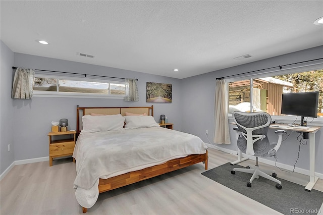 bedroom with light wood-style floors, baseboards, and visible vents