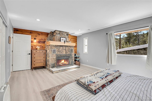 bedroom featuring baseboards, wood finished floors, wood walls, a fireplace, and recessed lighting