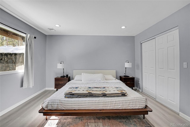 bedroom with baseboards, visible vents, and wood finished floors