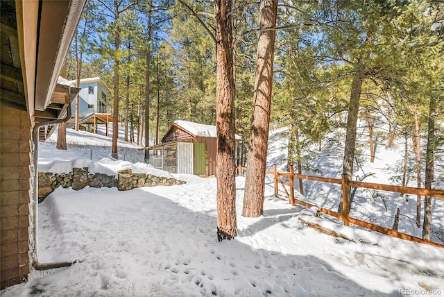 snowy yard with a shed and an outdoor structure