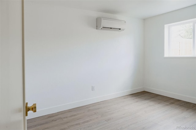 empty room featuring light wood-type flooring and an AC wall unit