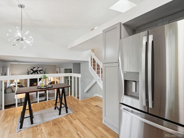 kitchen with a chandelier, gray cabinets, stainless steel fridge, and light hardwood / wood-style floors